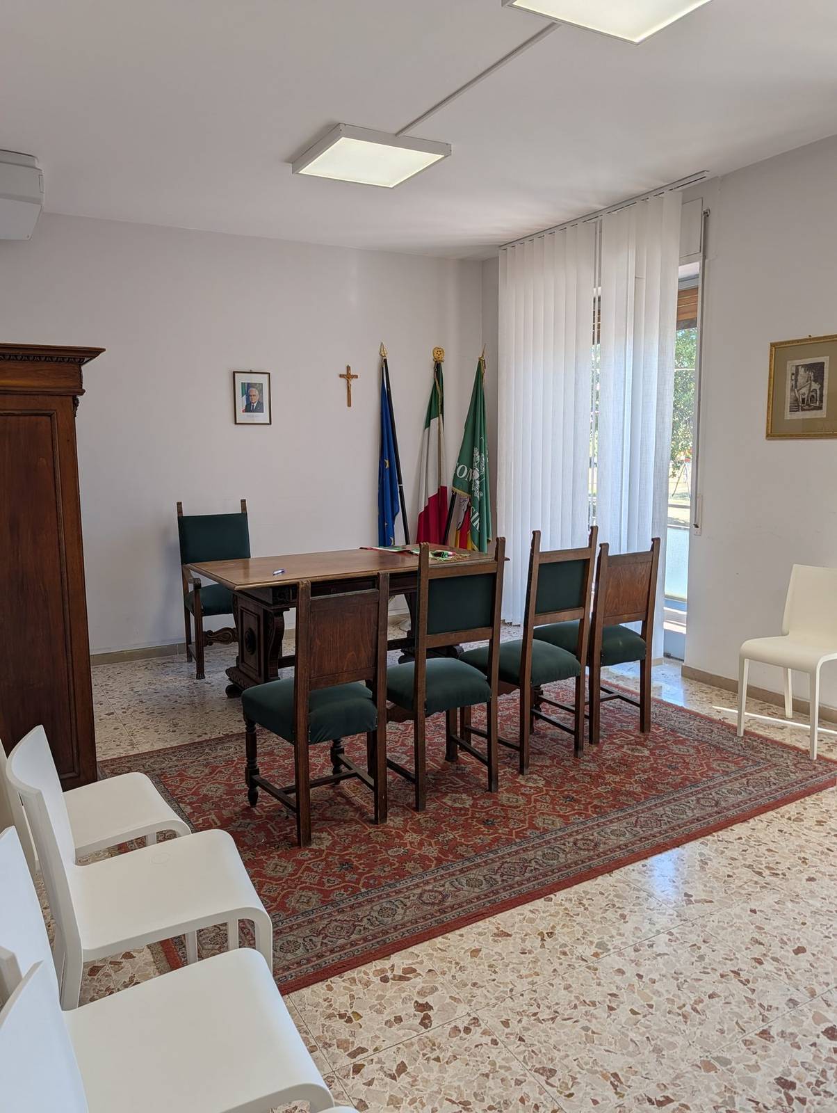 The saloncino at the Anagrafe offices, a plain room with flags and a desk